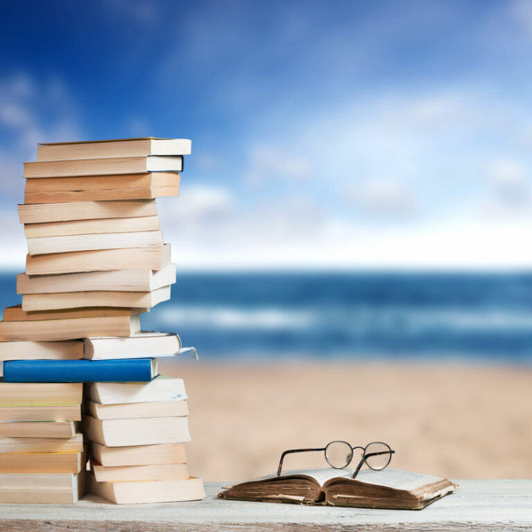 Stack of Travel Guides before a empty Beach