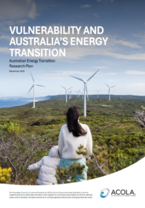 Woman and child on a green mountain side with their backs turned to us, looking at a horizon with wind turbines.